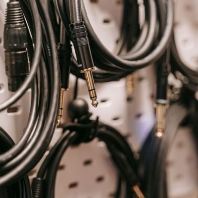 A detailed view of hanging audio cables with various connectors on a perforated board.