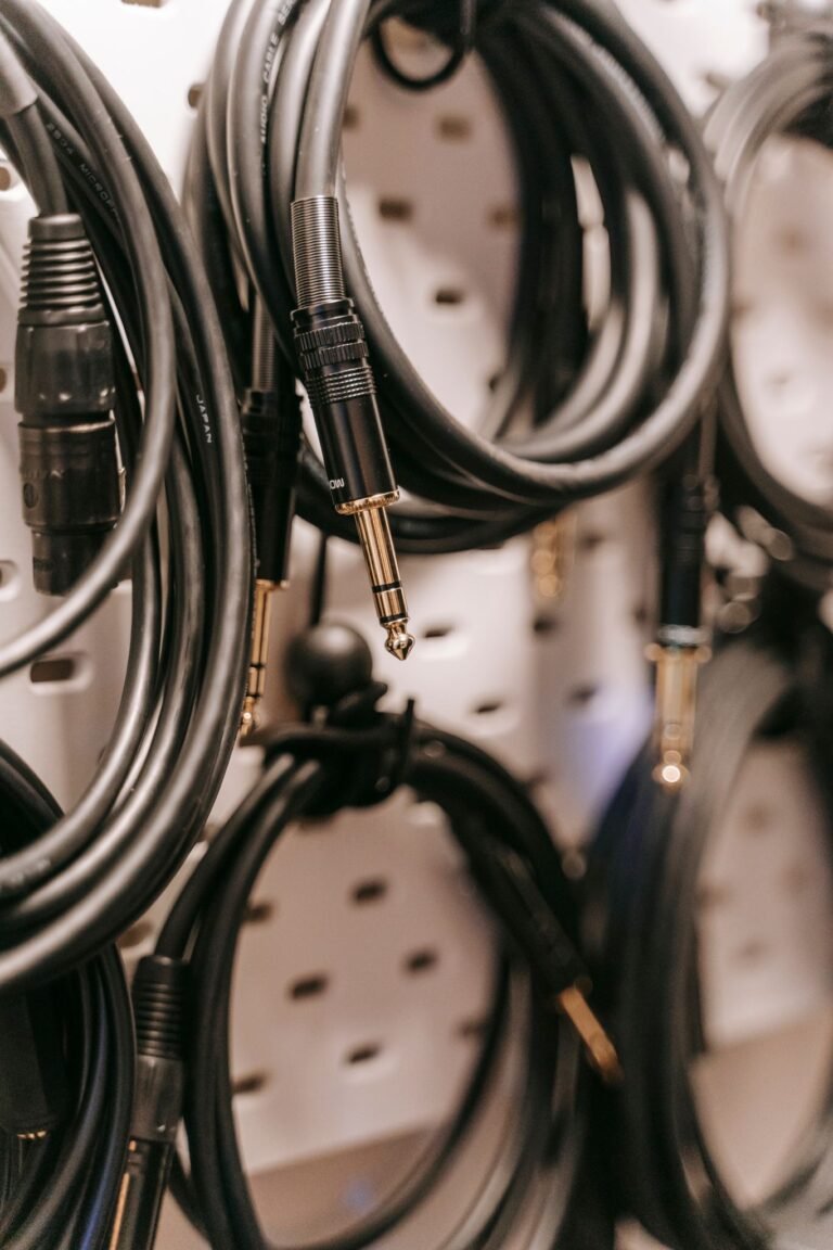 A detailed view of hanging audio cables with various connectors on a perforated board.