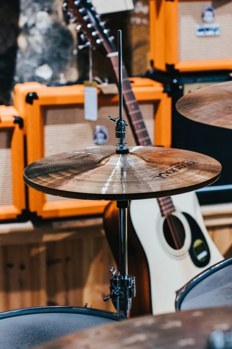 Close-up of cymbal with guitars and amplifiers in a music store setting.