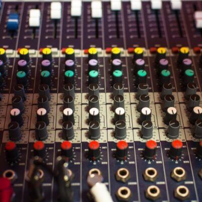 Detailed view of a professional audio mixing console with multicolored knobs in a studio setting.